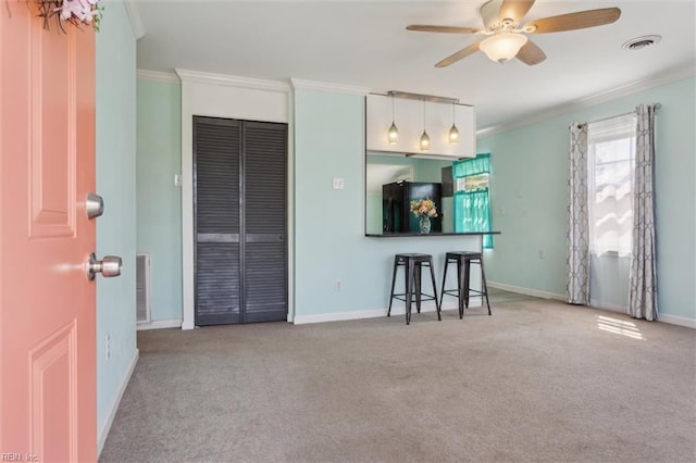 carpeted living area featuring baseboards, visible vents, a ceiling fan, and crown molding