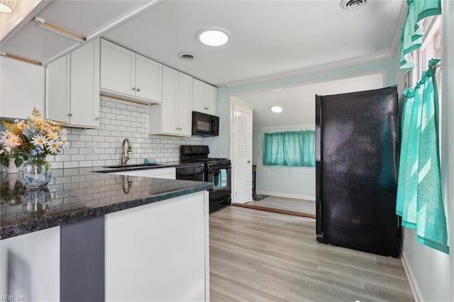 kitchen featuring a sink, decorative backsplash, black appliances, white cabinetry, and baseboards