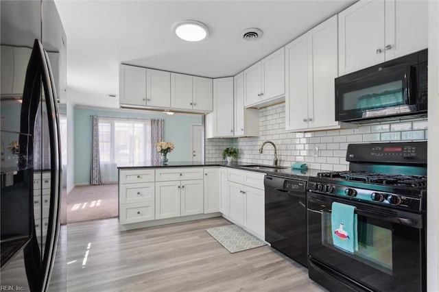 kitchen with a sink, visible vents, dark countertops, black appliances, and a peninsula