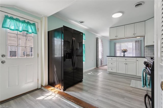 kitchen with crown molding, black appliances, a peninsula, light wood-style flooring, and white cabinets
