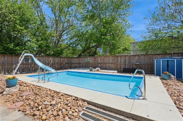 view of swimming pool with an outdoor structure, a fenced in pool, a storage unit, a water slide, and a fenced backyard
