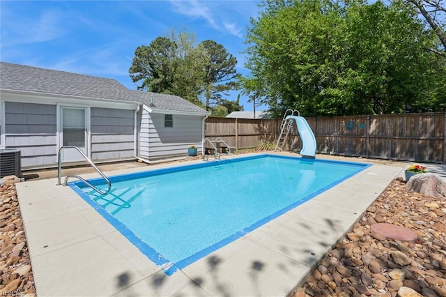 view of pool featuring a fenced in pool, central air condition unit, a fenced backyard, and a water slide