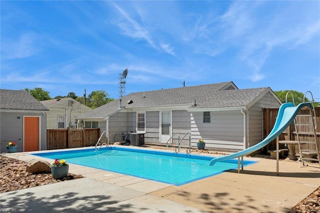 view of pool with a patio, a fenced in pool, a water slide, fence, and central AC
