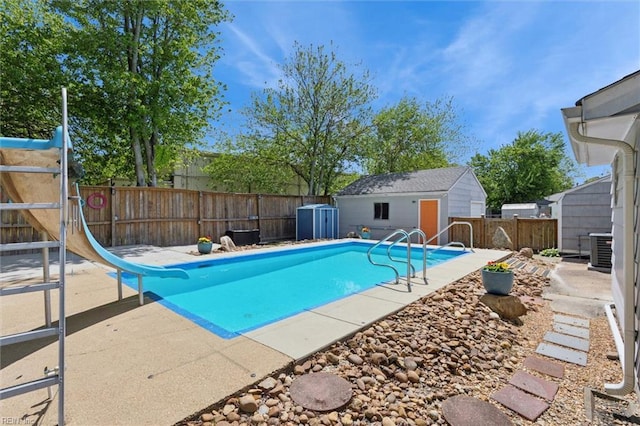 view of swimming pool with a patio area, central AC unit, a fenced in pool, a fenced backyard, and a water slide
