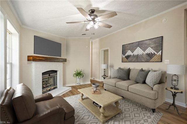 living room with wood finished floors, a brick fireplace, a ceiling fan, and ornamental molding