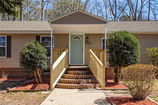 entrance to property featuring roof with shingles
