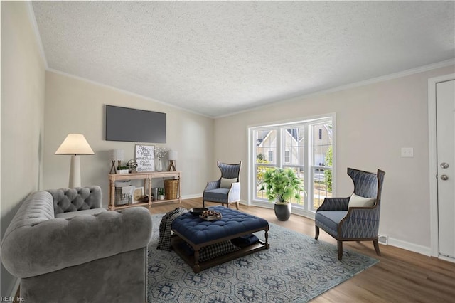 living room with wood finished floors, a textured ceiling, crown molding, and baseboards