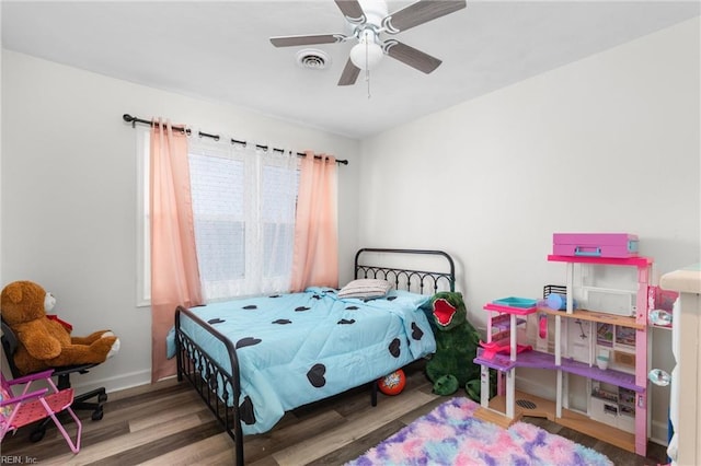 bedroom featuring wood finished floors, visible vents, a ceiling fan, and baseboards