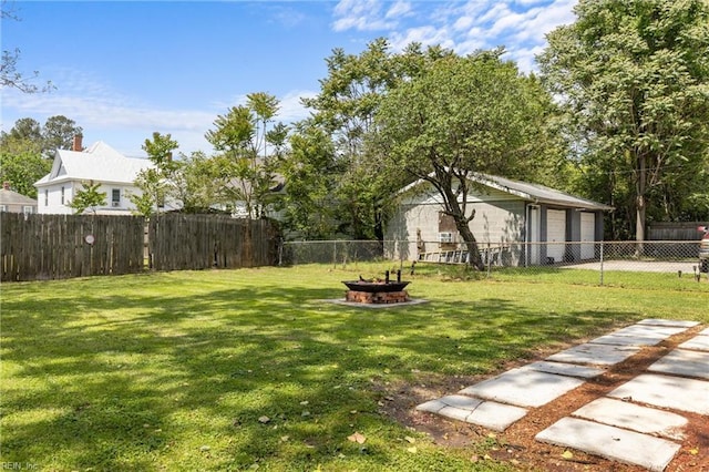 view of yard featuring a fenced backyard, an outdoor fire pit, and a garage