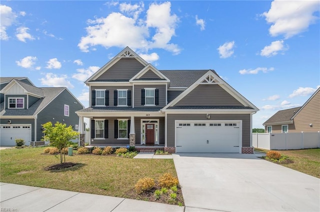 craftsman inspired home with a front yard, concrete driveway, covered porch, and fence