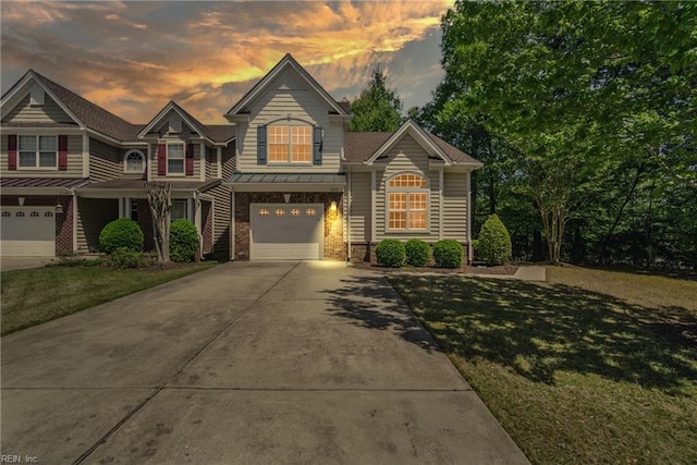 view of front of property with a yard, a standing seam roof, metal roof, a garage, and driveway