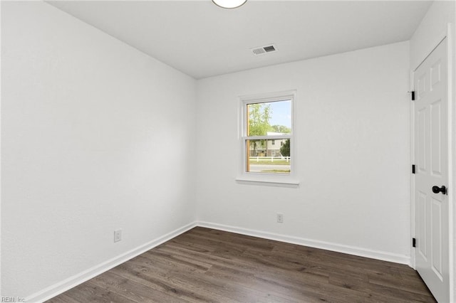 empty room with visible vents, baseboards, and dark wood-type flooring