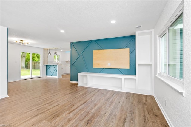 unfurnished living room with baseboards, wood finished floors, visible vents, and recessed lighting