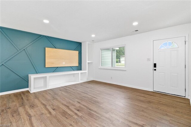 unfurnished living room featuring baseboards, wood finished floors, visible vents, and recessed lighting