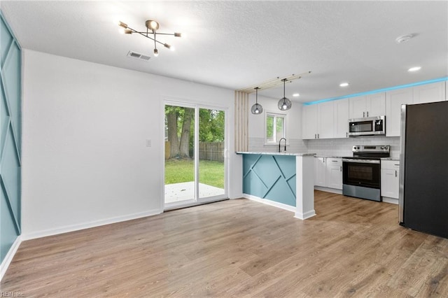 kitchen featuring tasteful backsplash, visible vents, white cabinetry, and stainless steel appliances