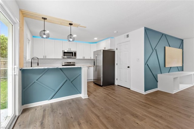 kitchen with white cabinets, backsplash, wood finished floors, and stainless steel appliances