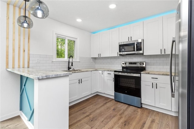 kitchen featuring white cabinets, wood finished floors, appliances with stainless steel finishes, and a sink