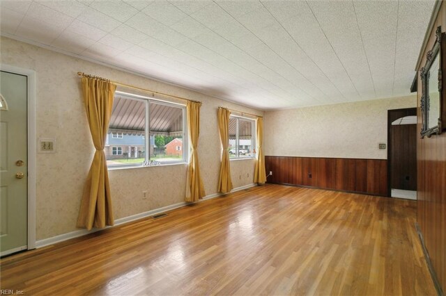 empty room with visible vents, wood finished floors, and wood walls
