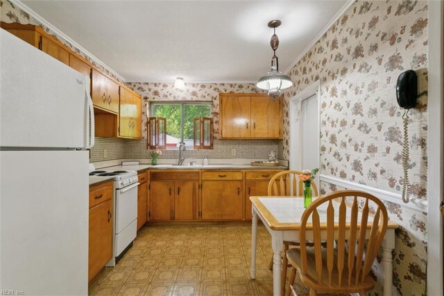 kitchen with wallpapered walls, light floors, a sink, white appliances, and crown molding