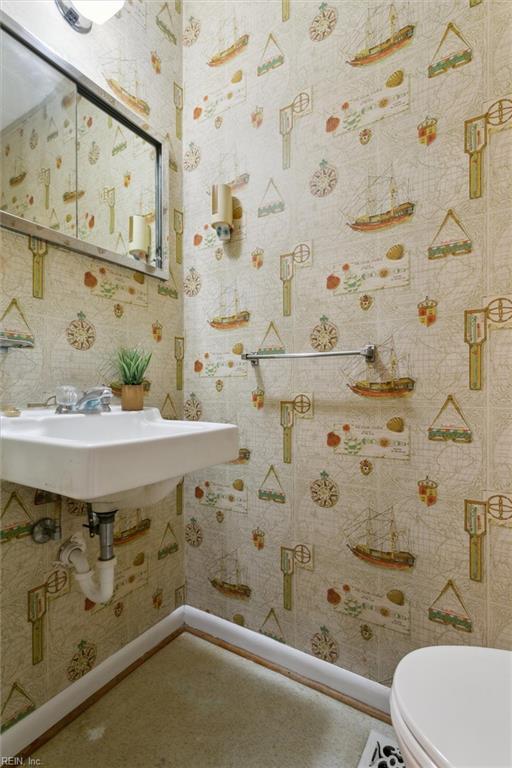 bathroom with wallpapered walls, baseboards, and toilet