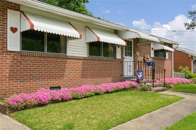 view of front facade with brick siding and a front lawn