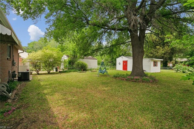 view of yard featuring a storage shed, central air condition unit, and an outbuilding