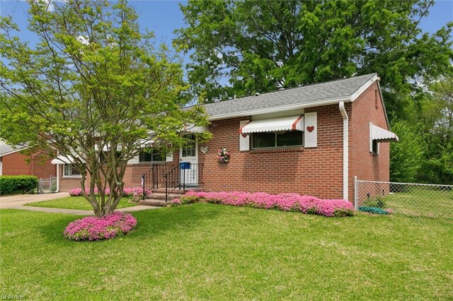 view of front facade featuring brick siding, a front lawn, and fence