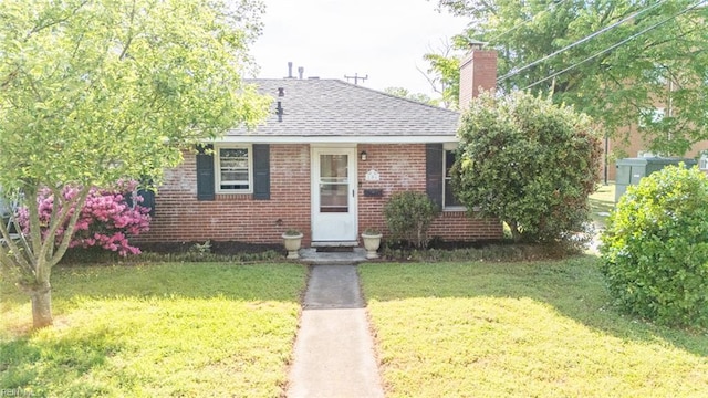bungalow-style house with a shingled roof, a front lawn, a chimney, and brick siding