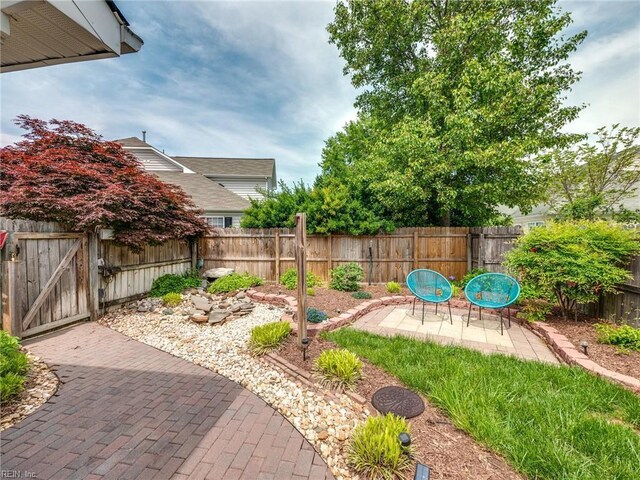 view of yard featuring a fenced backyard, a gate, and a patio area