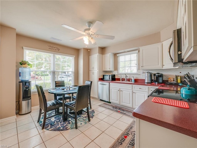 kitchen featuring dark countertops, a ceiling fan, light tile patterned floors, white cabinetry, and appliances with stainless steel finishes