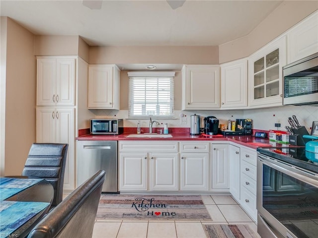 kitchen with white cabinets, dark countertops, a sink, and appliances with stainless steel finishes