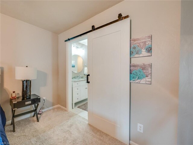 interior space with a barn door, light carpet, a sink, and baseboards