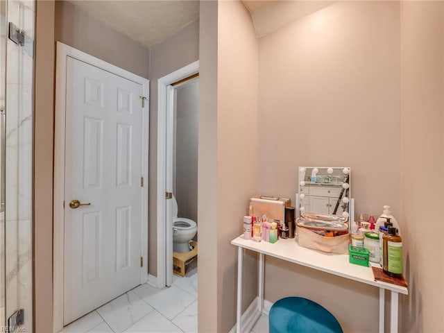 bathroom with baseboards, marble finish floor, and toilet