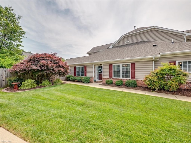 view of front of house featuring fence, a shingled roof, a front lawn, and brick siding