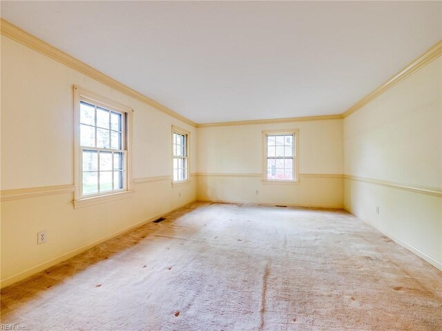 carpeted empty room featuring baseboards, ornamental molding, and plenty of natural light