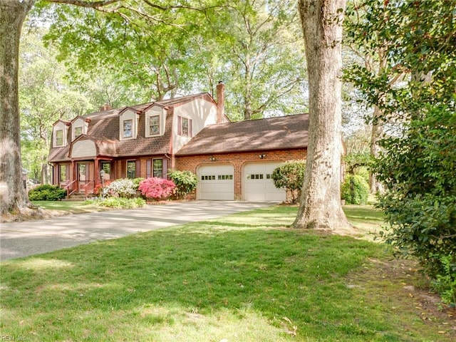view of front of home with a front lawn, driveway, a chimney, a garage, and a gambrel roof