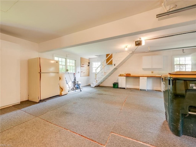 basement featuring plenty of natural light, freestanding refrigerator, and stairs