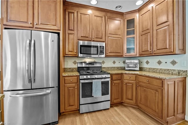 4011 E Providence Rd, Williamsburg, VA 23188 - kitchen with brown cabinetry, light stone counters, stainless steel appliances, and glass insert cabinets