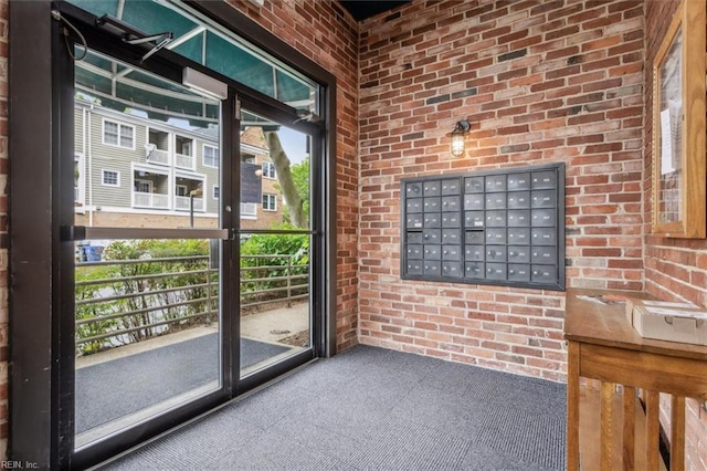 doorway to outside with carpet, mail area, and brick wall