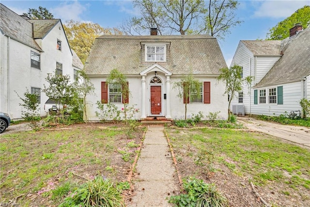 view of front of home with a chimney, central AC unit, and stucco siding