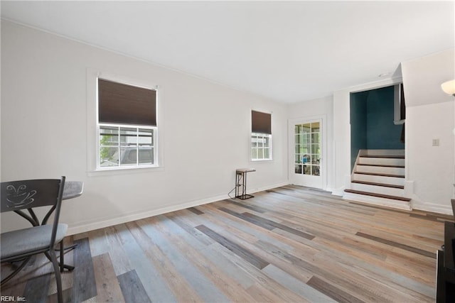 unfurnished living room featuring stairway, baseboards, and wood finished floors