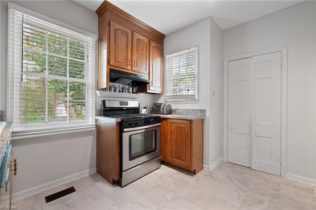 kitchen with brown cabinetry, baseboards, under cabinet range hood, gas stove, and visible vents