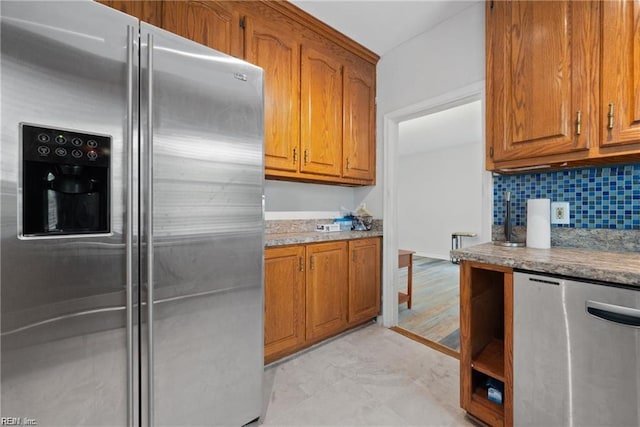 kitchen with refrigerator, brown cabinetry, backsplash, and stainless steel fridge