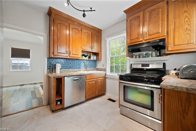kitchen with open shelves, a sink, brown cabinetry, appliances with stainless steel finishes, and under cabinet range hood