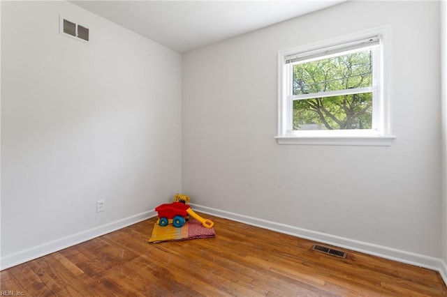 empty room with visible vents, wood finished floors, and baseboards