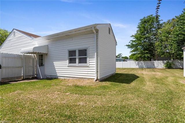 rear view of property featuring fence and a yard