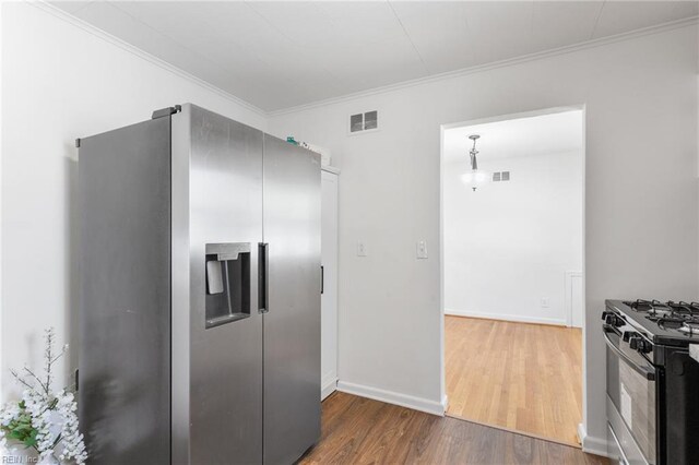 kitchen featuring visible vents, stainless steel appliances, wood finished floors, and crown molding