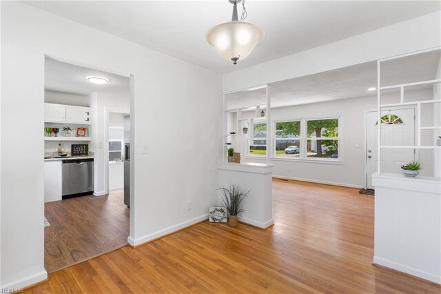 unfurnished dining area featuring baseboards and light wood-style flooring