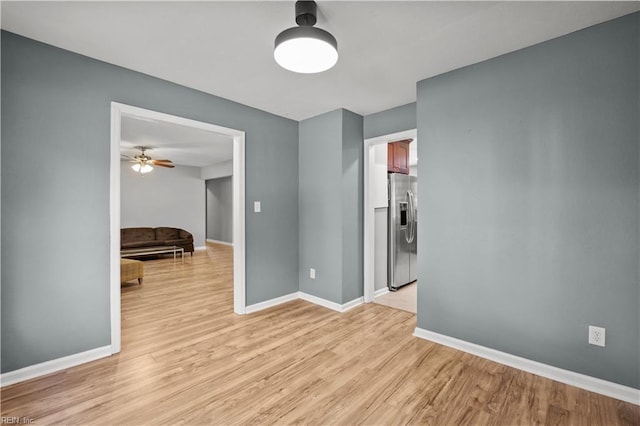 empty room with baseboards, ceiling fan, and light wood-style flooring