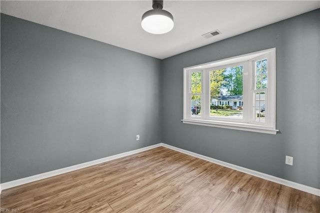 unfurnished room featuring visible vents, baseboards, and wood finished floors